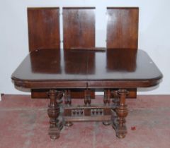 Antique-style oak extending dining table with three additional leaves, on central balustrade