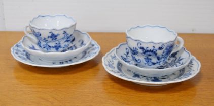 Two Meissen blue and white 'Blue Onion' pattern porcelain trios, comprising a cup, saucer and side