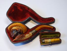 Meerschaum pipe carved as the head of a man with hat, also an amber cigarette holder with silver