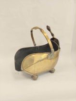 Brass swing handle coal scuttle on bun feet with shovel.