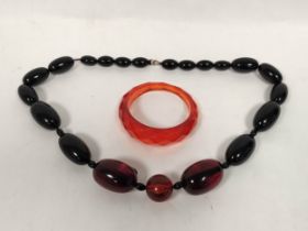 Amber bead necklace of graduated oval beads and a faceted bangle.