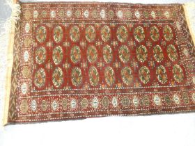 Tekke hand knotted rug with nine rows of three geometric motifs on red ground, 190cm x 125cm