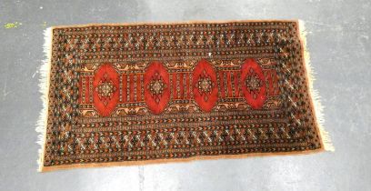 Belouch rug with geometric medallions to the centre on red ground, with further motifs to the