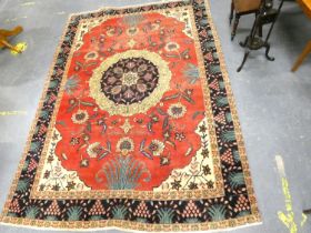 Traditional Tabriz rug with floral medallion to the centre within foliate swags on red ground with