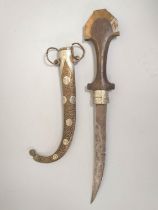 Arabic Jambiya dagger of elongated form with white metal and brass mounts and wooden handle.