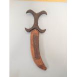 A Sudanese Beja dagger with sharply curving blade and characteristic X-form carved wooden handle