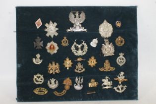 Board of military cap badges, shoulder titles and buttons to include Kings Own Scottish Borderers,