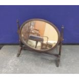 Mahogany toilet mirror with oval plate upon turned supports and shaped feet, 19½"