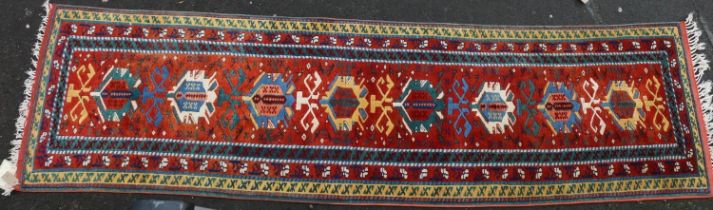 Turkish wool runner, the geometric motifs on red ground within polychrome borders, 298cm x 82cm.