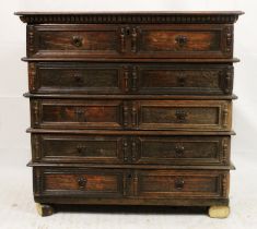 An antique oak chest of drawers, 17th to 18th century, the dark oak boarded top above five long