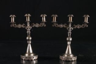 Pair of European Colonial white metal taper sticks, the three sconces on scrolled floral arms,