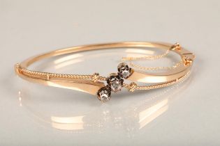 Yellow metal and three stone diamond bangle, the hinged bangle with twisted wirework frame set