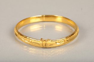 Chinese yellow gold bangle, the textured surface engraved with floral designs, internal W5.7cm, 21g,