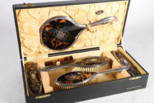 George V silver and tortoiseshell dressing table set consisting of mirror, two handled brushes,