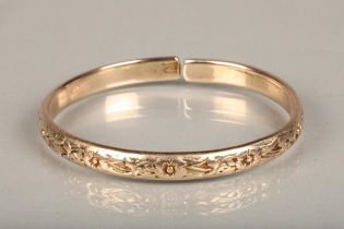 Rose gold coloured yellow metal West Indian bayras bangle with floral pattern, unhallmaked but