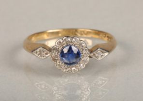 An Art Deco period sapphire and diamond daisy cluster ring, the central round cut sapphire set