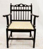 19th century ebonised 'drunkards' style low armchair, the pierced top rail leading to spindle back