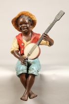 Large Bretby terracotta painted figure of a seated boy playing a banjo, 53cm high.