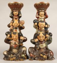 Pair of Chinese pottery figure stands, each with a figure with two children on their shoulders