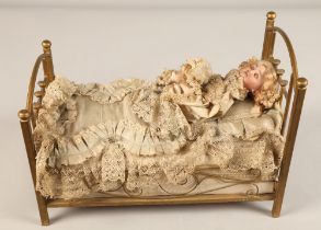 A 19th century musical automaton in the form of a Victorian doll lying in a brass bedstead and