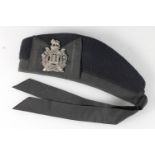 Unhallmarked white metal Kings Own Scottish Borderers white metal cap badge on a black cloth