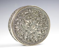 A white metal box and cover, possibly Indian, the pull off circular cover with embossed scrolling