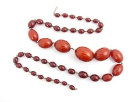 A string of cherry coloured 'amber' beads, the forty two graduated polished oval beads with base