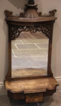 A 19th century style carved oak mirror back wall shelf, the pagoda top above scroll carved