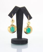 A pair of yellow metal and untested emerald earrings, the circular discs with central oval cut
