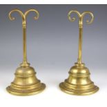 A pair of brass door porters, 19th century, of bell form, each handle with two scrolls, each 24cm