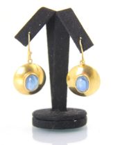 A pair of yellow metal and untested sapphire earrings, the central oval cabochon within a yellow
