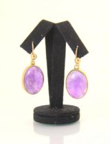A pair of amethyst earrings, the oval cabochons within yellow metal rob over mount, with shepherd