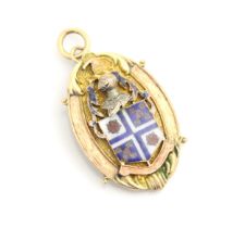 A yellow metal pedant, the oval pendant with applied enamel shield motif surmounted by a knight,