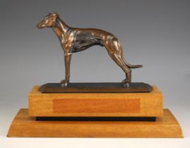 A bronze patinated spelter greyhound, modelled standing, set to a stepped wooden and ebonised