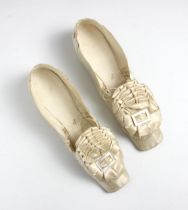 A pair of ivory silk satin ladies shoes, circa 1850, with rosette and mother of pearl button to