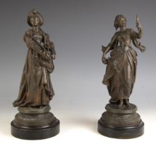 A near pair of spelter figures, 20th century, one modelled as a well dressed lady holding a