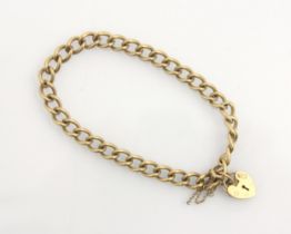 A 9ct yellow gold bracelet, the curb link chain suspending a heart shaped padlock fastener, some