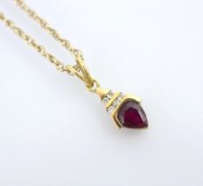 An untested ruby and diamond pendant, the pear cut red stone within yellow metal mount surmounted by