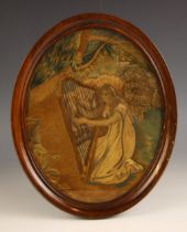 An oval silkwork picture, 19th century, depicting a young kneeling girl playing the harp in a