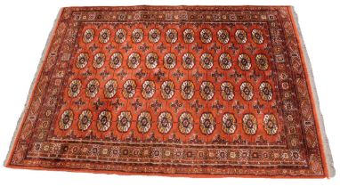 A Bohkara pattern rug, the four rows of eleven octagonal guls, upon a copper coloured ground, within
