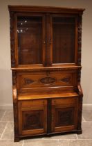 A carved golden oak secretaire bookcase, late 19th century, probably Welsh, the moulded cornice over