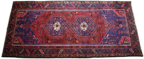 A terracotta and blue ground full pile Persian Hamadan Lori village rug, the central red field