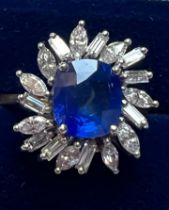 A 1960's sapphire and diamond cluster ring, the central cushion cut sapphire within white metal claw