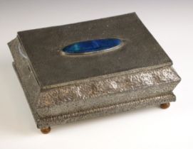 An Art Nouveau hammered pewter jewellery box, the hinged cover centered with an oval blue Ruskin