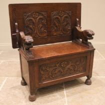 A 17th century style carved oak monks bench, early 20th century, the slide over panel carved with