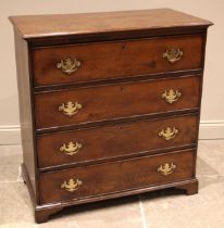 A late George III oak chest of drawers, the moulded plank top over an arrangement of four invert