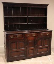 An early 18th century oak Welsh dresser, the enclosed plate rack with a moulded cornice over two