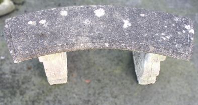 A reconstituted stone bench, of curved form, upon twin scroll moulded pedestal supports, 43cm H x
