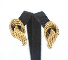 A pair of yellow metal earrings, the stylised knot studs with engraved detail, with screw and