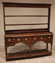 A George III oak and elm dresser, the open plate rack with a moulded dentil cornice over a plain